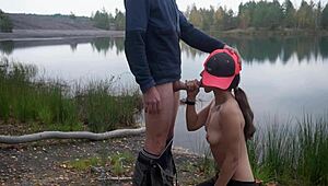 A brunette woman gives a public blowjob by the lake in a homemade video