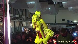 Blondes ripping clothes in intense lesbian sex show on public outdoor stage with dildos and voyeurs watching