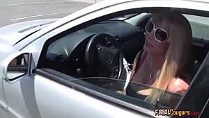 Mature blonde cougar in dress meets muscular bodybuilder in outdoor car.