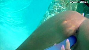 Nora Shmandora performs underwater self-sex with a purple dildo in the pool, naked and using toys.