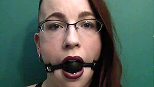 dark lipstick BALLGAG DROOLING with intense eye contact in close-up.