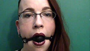 dark lipstick BALLGAG DROOLING with intense eye contact in close-up.