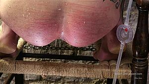 Syringed while kneeling, she endures intense anal stretching session