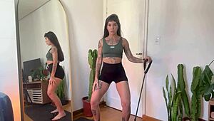 An inked girl warms up with rubber bands for her yoga fitness routine.