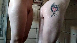 Pale blonde and brunette WASHING each other with loofah in SHOWER close-up