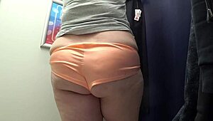 The camera watches a curvy milf change in satin panties