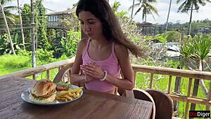 Cute girl feels excited eating burger with cum on face in public cafe