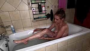Skinny milf strips red dress, shaves legs and pussy in bubbly bath.