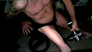 Skinny old woman applies percussion massager to thigh in underwear on stool
