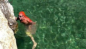 yellow trunks hug her curves against blue waves flashing wet shaved pussy outdoors